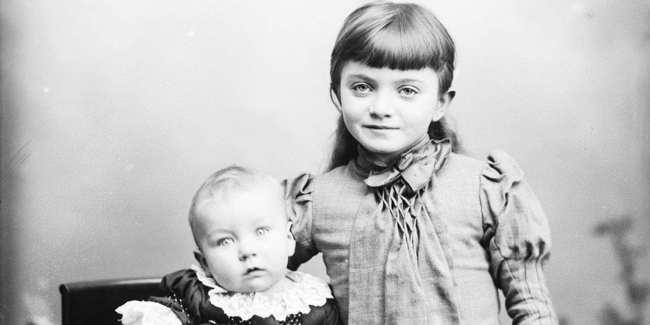 Portrætfotografi af en lille pige og en baby med fint tøj på.