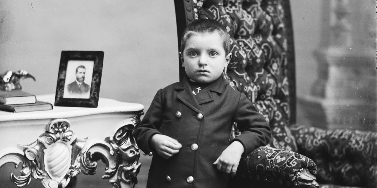 Portrætfotografi af en lille dreng i fint tøj i en stue.