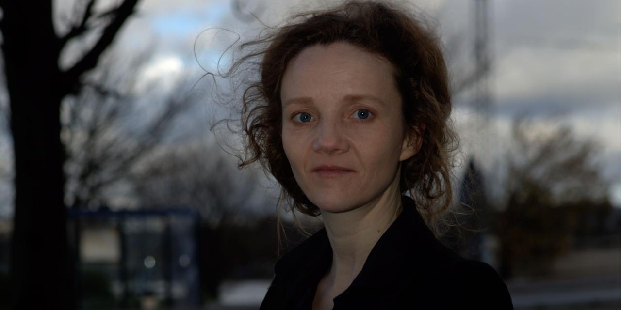 Billede af Ursula A. Olsen med en mørkere baggrund med skyer og et vissent træ.