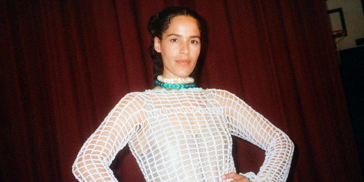 Billede af ANYA stående foran et rødt tæppe med hænderne i siden.