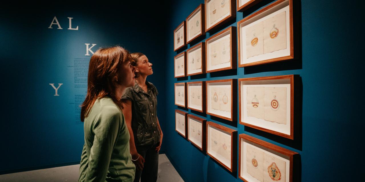 Gæster kigger på genstande i billedrammer i udstillingen.