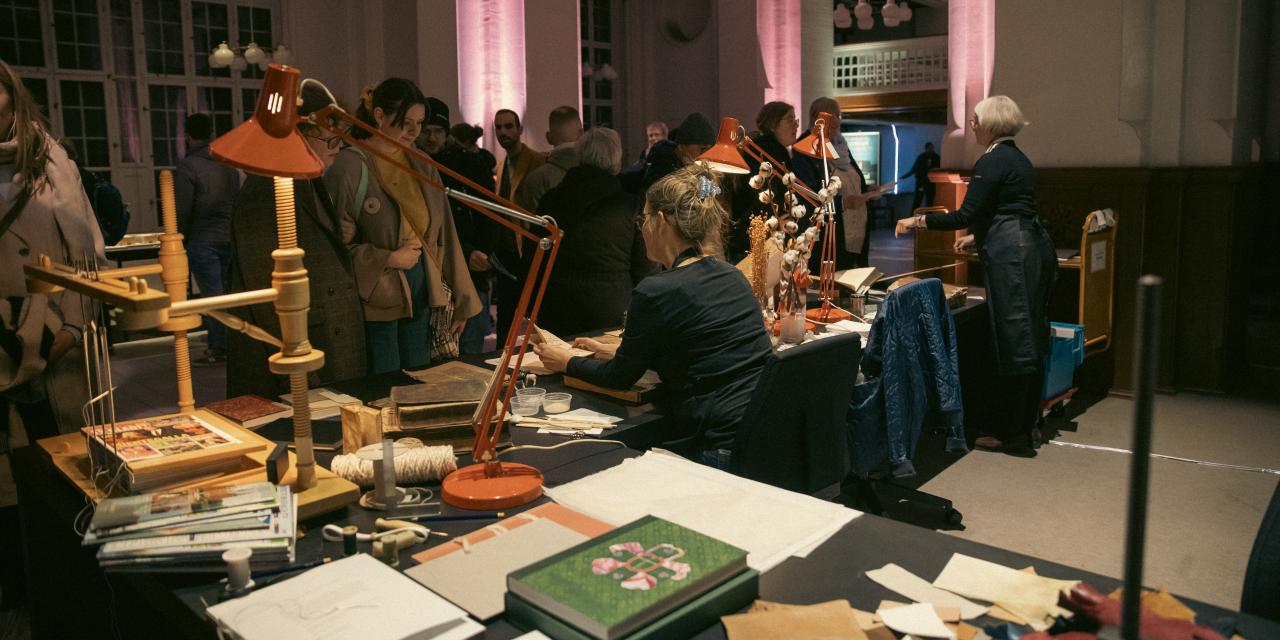 To medarbejdere fra Det Kgl. Bibliotek sidder omgivet af bøger og andre materialer