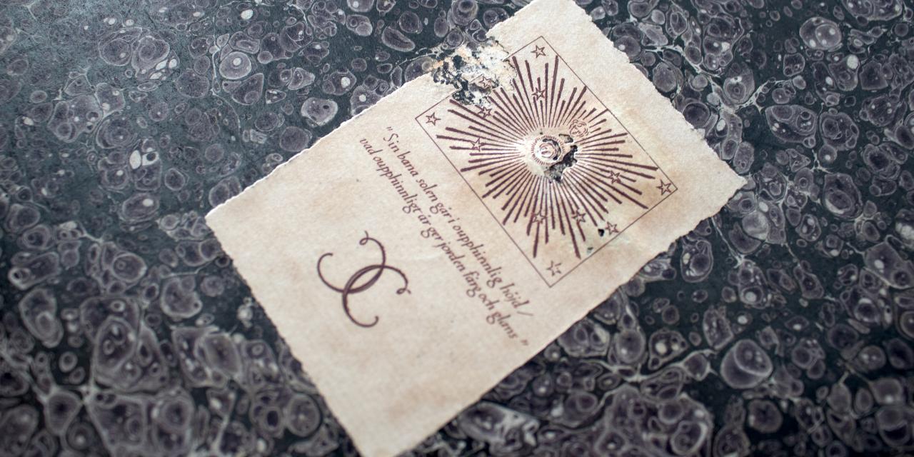 Gammel side fra bog med skrift og illustrationer i mørkerød.