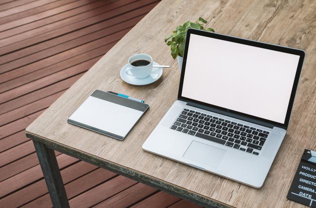 Bord med laptop, kaffe og skriveredskaber