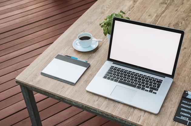 Table with laptop, coffee and writing utensils