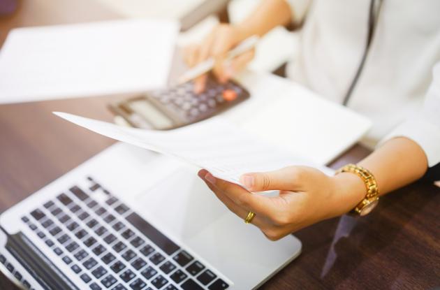 Laptop, calculator and hands with paper