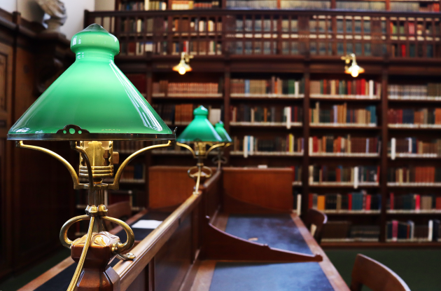 Reading room with classic green lamps and books on shelves