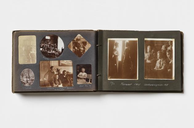 Et fotoalbum ligger åbent med to sider dækket af gamle familiebilleder