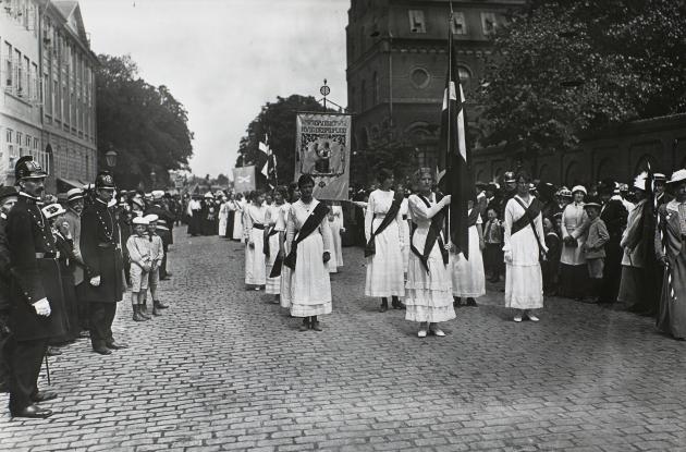 Kvindetoget på vej mod Amalienborg. Kvinderne bærer hvide kjole og bannere.