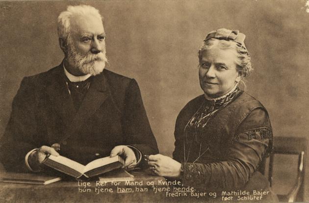 Frederik Bajer sidder med en bog. Hans kone, Mathilde Bajer, sidder ved hans side.