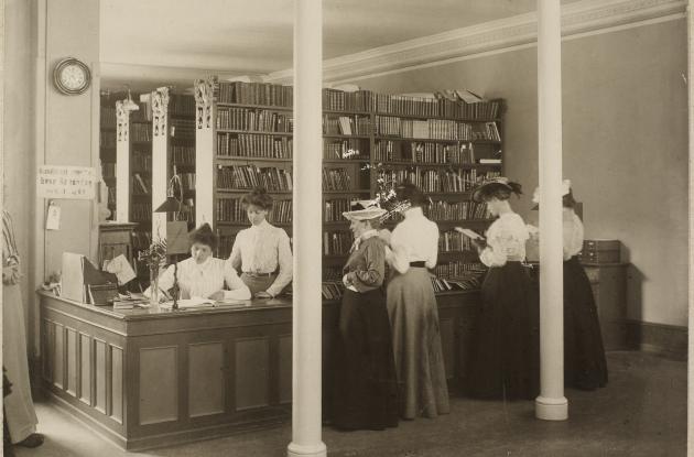 Kvinder ved skranke på bibliotek læser