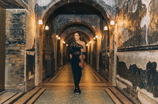 Violinist Nicola Benedetti walks down a hallway in an old building