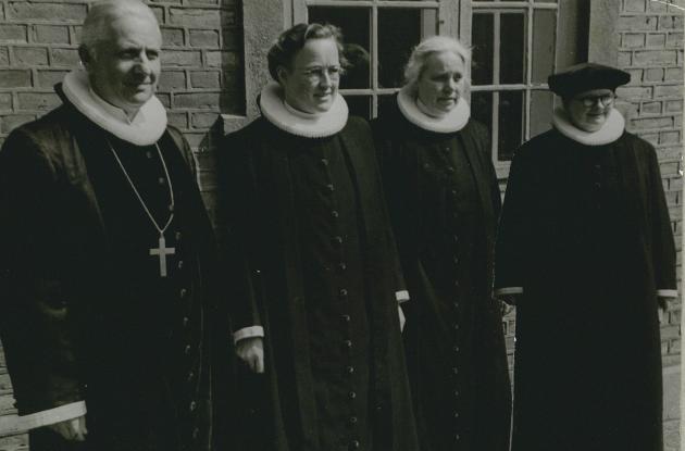 A male priest and three female priests stand side by side.