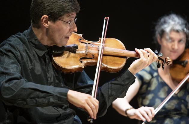 Two violinists play on stage in The Queen's Hall 