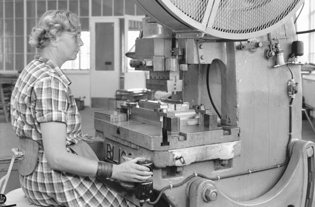 Kvinde sidder ved indstrimaskine i fabrikshal