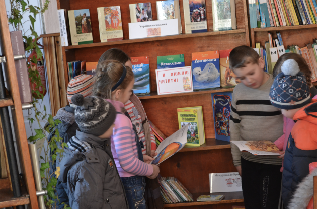 Ukrainian children look at books at a library in Turka near Lviv