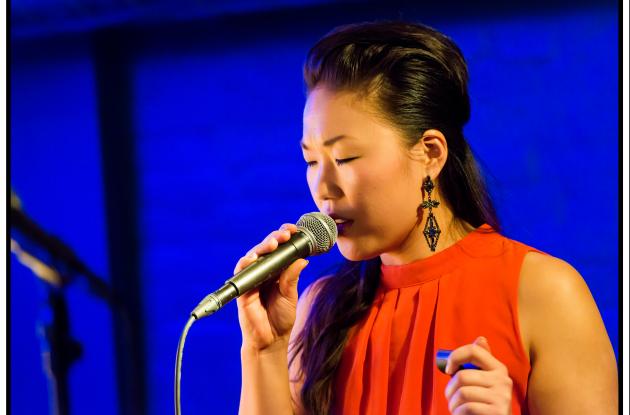 Birgitte Soojin sings on stage with a blue background