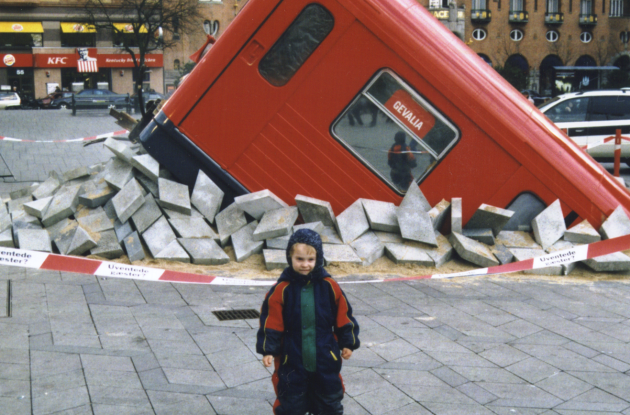 Manipulated image of a subway car that has run wild and has come up through the ground at Rådhuspladsen. In front stands a child in a flight suit.