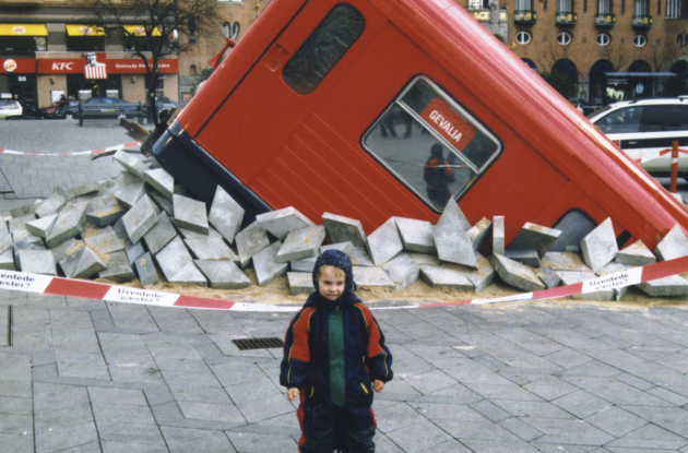 Subway car halfway through the ground. In front stands a small child.