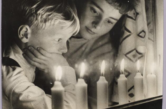 Fotografi af en kvinde og et barn, som kigger på de levende lys, der brænder i vinduet 4. maj.