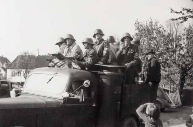 Photograph of armed resistance fighters in the trunk of a car.