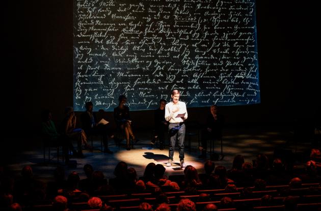 Actor stands on stage and recites