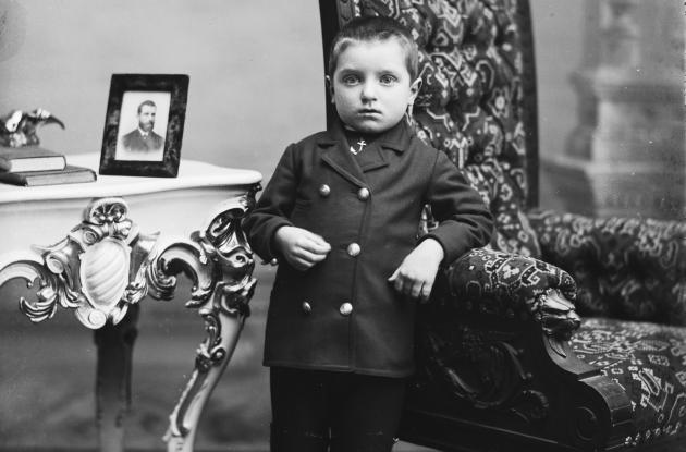 Portrætfotografi af en lille dreng i fint tøj i en stue.