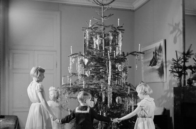 Fotografi af børn, der danser om et juletræ