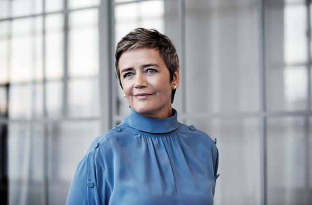 Fotografi af Margrethe Vestager foran glasbygning