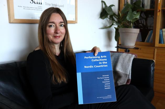 Seniorforsker Anna Lawaetz viser bogen "Performing Arts Collections in the Nordic Countries" frem.