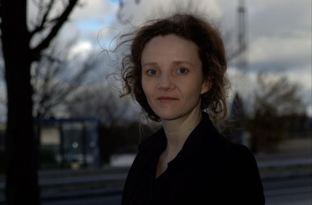 Billede af Ursula A. Olsen med en mørkere baggrund med skyer og et vissent træ.