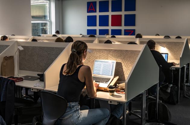 Pige med ryggen til sidder og arbejder på læsesal.