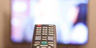 Remote control in front of TV screen