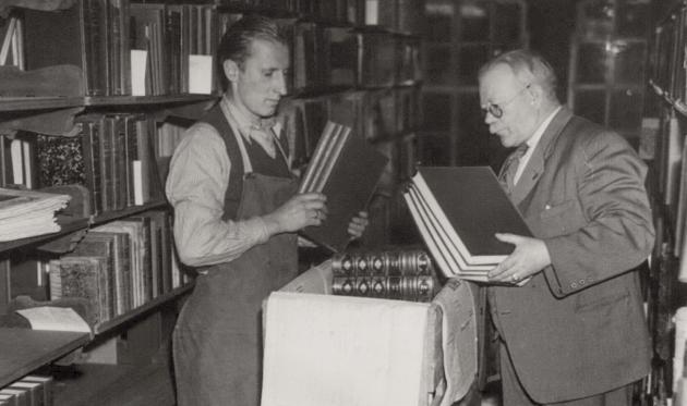 Biblioteksmedarbejdere blandt bøger og reoler. Ældre