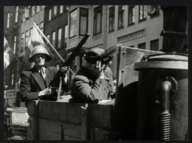 Liberation 1945: Freedom fighter guards elderly lady in the barn of truck