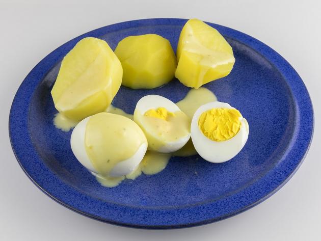 Hard-boiled eggs in mustard sauce on blue plate
