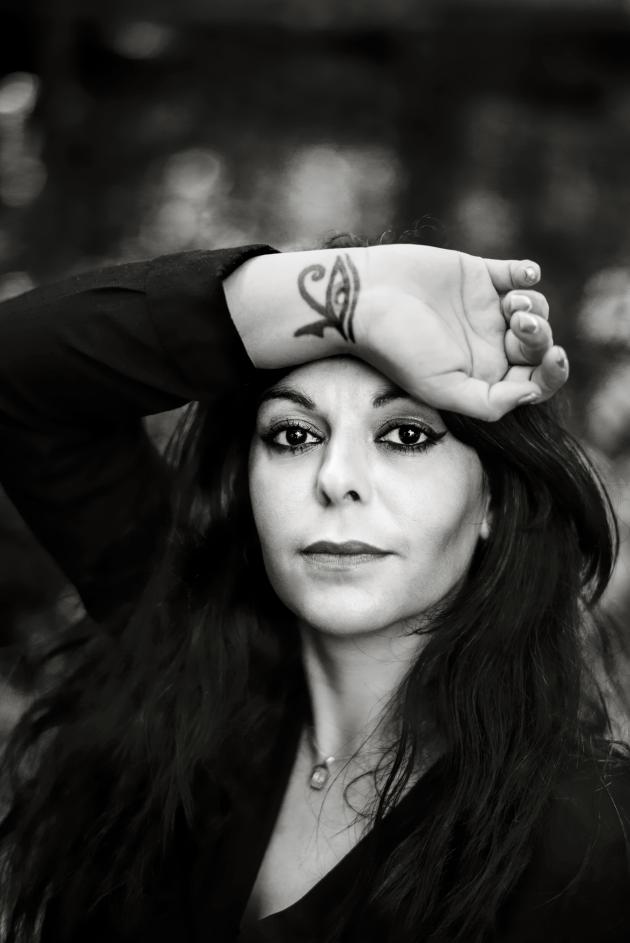 Black/white photo of woman holding her tattooed wrist up on her forehead