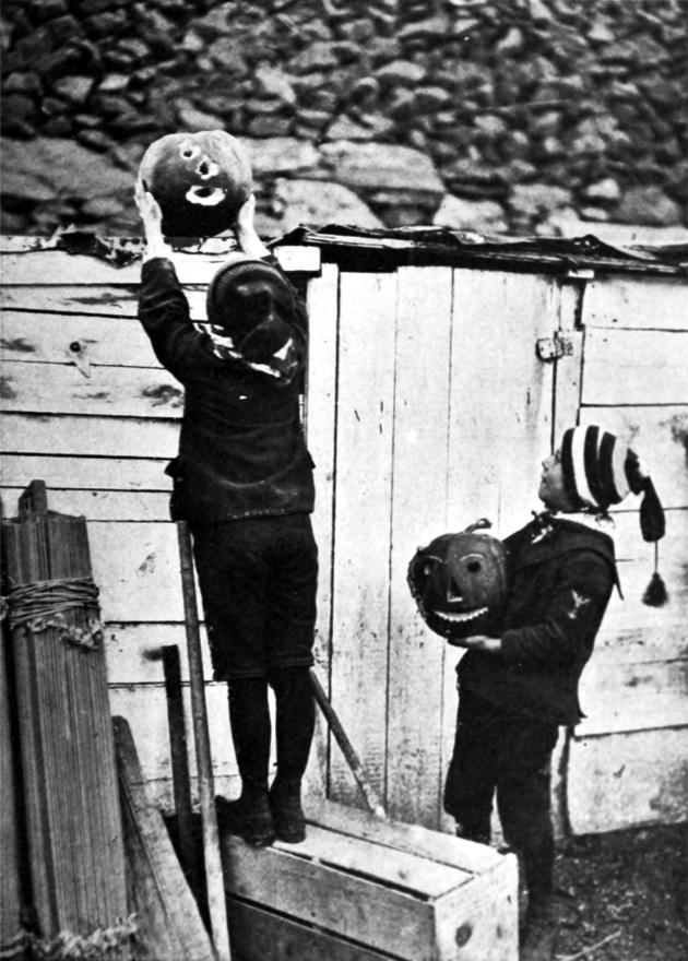 Black and white photo of two boys putting up pumpkin lanterns for Halloween.