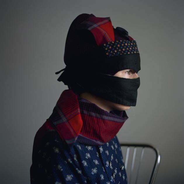 En kvinde sidder i profil med hovedet dækket af en strudemaske