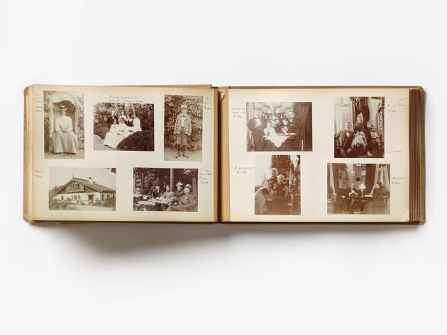 An open photo album with two pages covered with nine pictures in sepia