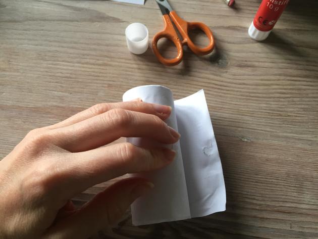 A hand rolls a toilet roll over paper