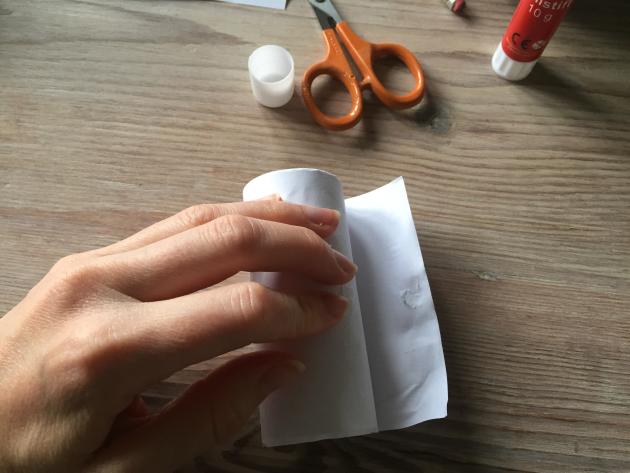 A hand rolls a toilet roll over paper