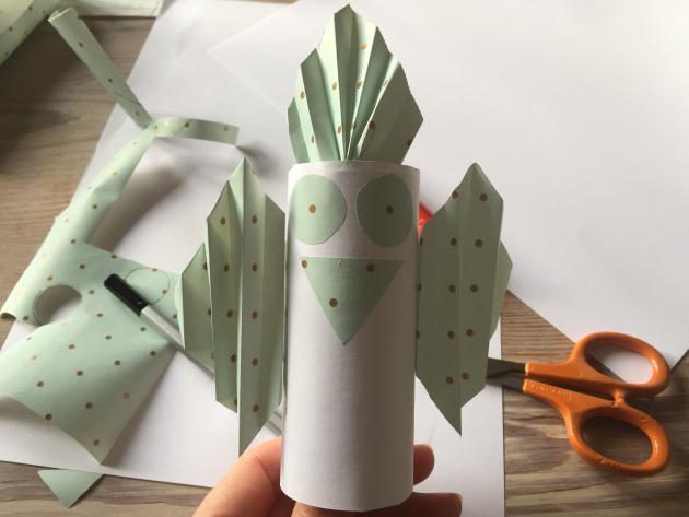 A bird made of a toilet roll and green paper