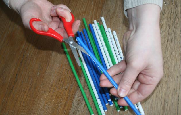 Two hands cut up colourful straws