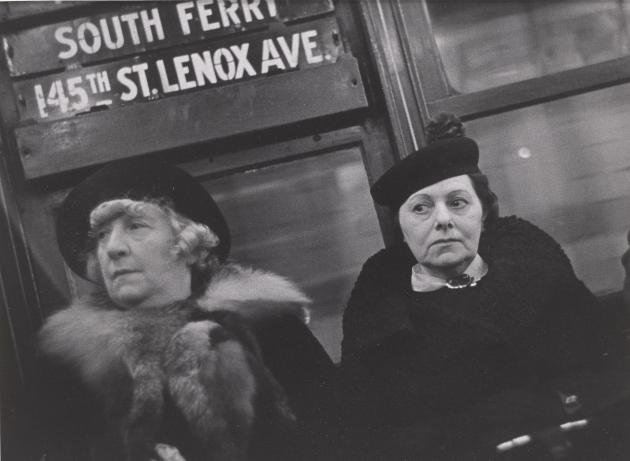 To kvinder sidder side om side i undergrundstog