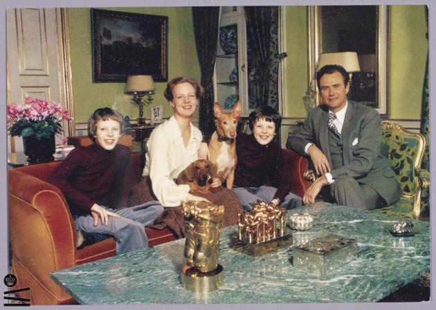 Dronning Margrethe II, prins Henrik, Kronprins Frederik og prins Joachim sidder i en sofa med deres hunde.