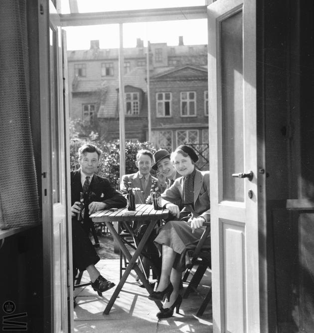 4 people drink beer in the sunshine on the terrace