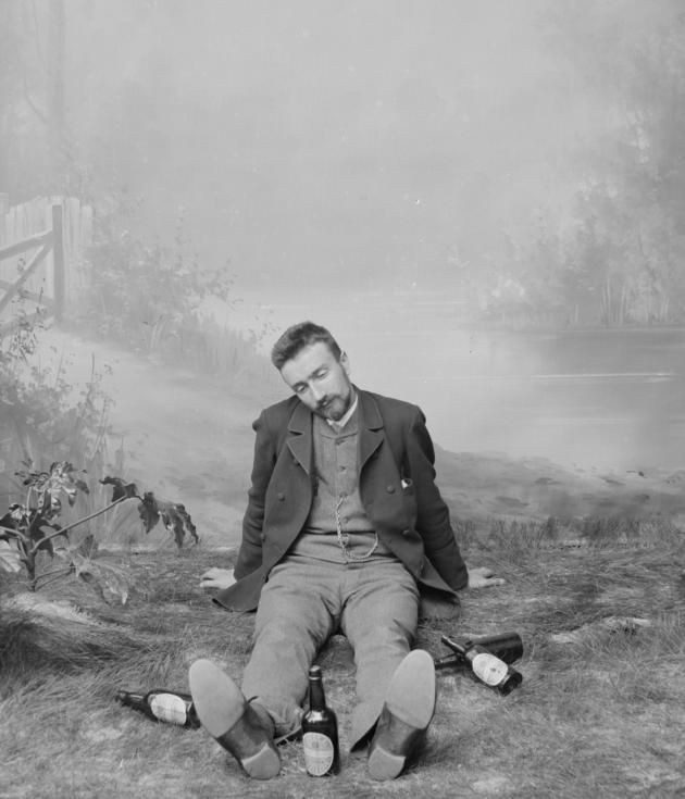 Elfelt sits on an artificial forest floor surrounded by beer bottles in his studio