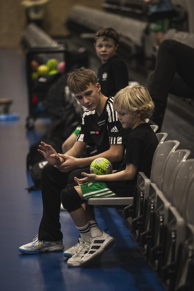 To drenge sidder med en håndbold og snakker.