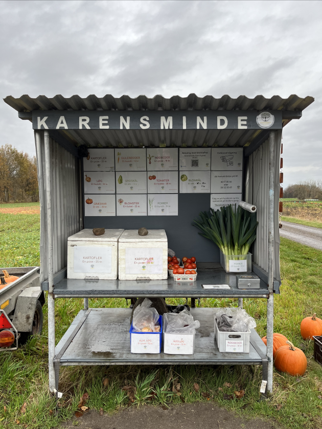 En ubemandet vejbod med græs og træer i baggrunden.